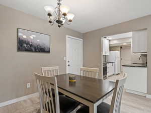 Dining space featuring a textured ceiling, sink, light wood-type flooring, and an inviting chandelier