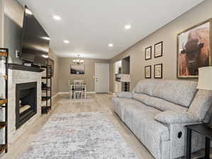 Living room with a chandelier, light wood-type flooring, and a fireplace