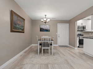 Dining space with a chandelier, a textured ceiling, and light hardwood / wood-style floors