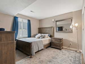 Bedroom with light carpet and a textured ceiling