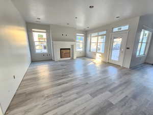 Unfurnished living room featuring light hardwood / wood-style floors and a brick fireplace