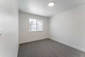 Carpeted empty room featuring visible vents, baseboards, and a textured ceiling