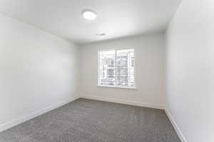 Carpeted spare room with baseboards, visible vents, and a textured ceiling