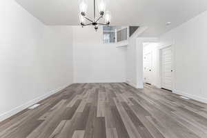 Unfurnished dining area with baseboards, a notable chandelier, and wood finished floors