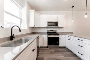 Kitchen featuring a sink, dark wood-type flooring, appliances with stainless steel finishes, and white cabinets