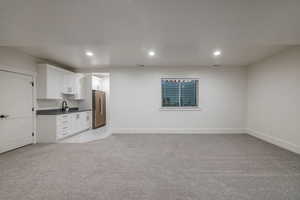 Unfurnished living room featuring light colored carpet and sink