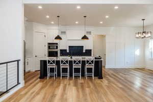 Kitchen featuring light hardwood / wood-style flooring, white cabinetry, and a center island with sink