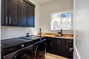 Washroom featuring cabinets, sink, washing machine and dryer, and light wood-type flooring