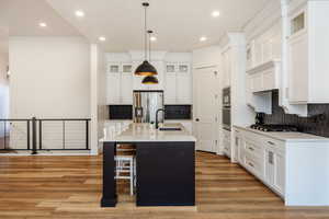 Kitchen featuring decorative backsplash, stainless steel appliances, a center island with sink, and sink