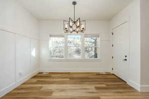 Unfurnished dining area featuring a chandelier and hardwood / wood-style floors