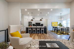 Living room with an inviting chandelier and light hardwood / wood-style flooringVirtually staged