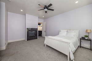 Carpeted bedroom featuring a fireplace and ceiling fan