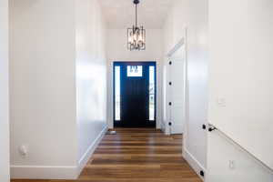 Foyer with a notable chandelier, a towering ceiling, and dark hardwood / wood-style flooring