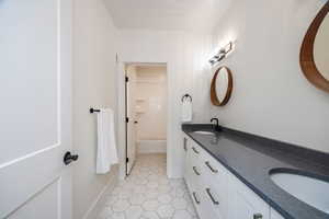 Bathroom with tiled shower / bath, vanity, and tile patterned flooring