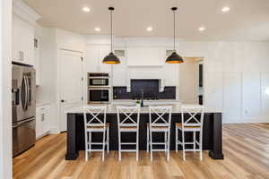 Kitchen featuring a center island with sink, appliances with stainless steel finishes, and light hardwood / wood-style floors