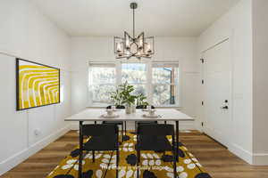 Dining space with wood-type flooring and a chandelierVirtually staged