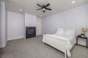 Carpeted bedroom featuring a fireplace and ceiling fan