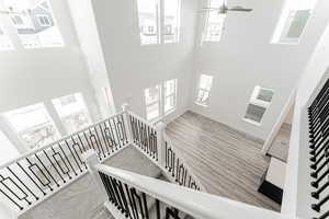 Stairs with ceiling fan, wood finished floors, and a towering ceiling