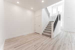 Staircase with recessed lighting, wood finished floors, and a chandelier