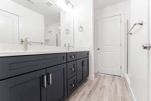 Bathroom with visible vents, a shower stall, double vanity, wood finished floors, and a sink