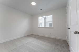 Spare room with visible vents, light colored carpet, and baseboards