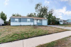 Ranch-style home featuring a garage and a front lawn