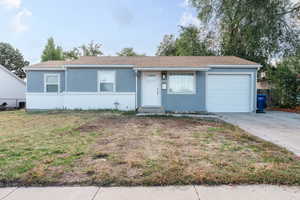 Single story home featuring a garage and a front lawn