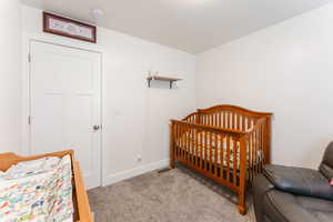 Bedroom with a nursery area and light colored carpet