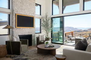 Living room featuring a high ceiling, a stone fireplace, and hardwood / wood-style flooring