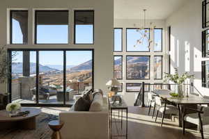 Living room with an inviting chandelier, a mountain view, a healthy amount of sunlight, and wood-type flooring