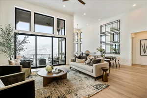 Living room featuring a high ceiling, light hardwood / wood-style flooring, a mountain view, and ceiling fan with notable chandelier