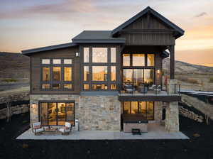 Back house at dusk featuring a patio area and an outdoor living space with a fireplace