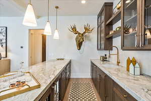 Kitchen with light stone counters, decorative light fixtures, light wood-type flooring, and backsplash