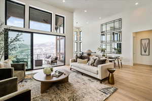 Living room with a chandelier, light hardwood / wood-style flooring, a mountain view, and a towering ceiling