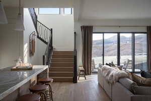 Living room with light hardwood / wood-style floors, a water and mountain view, and indoor bar