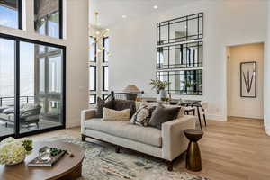 Living room with light hardwood / wood-style floors, a towering ceiling, and a chandelier