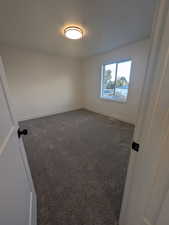 Unfurnished room featuring dark carpet