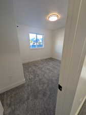 Unfurnished room featuring dark colored carpet