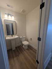 Bathroom with toilet and hardwood / wood-style flooring