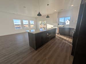 Kitchen with a kitchen island, white cabinetry, and a healthy amount of sunlight