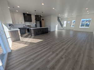 Kitchen featuring hanging light fixtures, a center island, hardwood / wood-style floors, and white cabinets