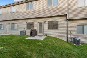 Rear view of property with a yard and central air condition unit