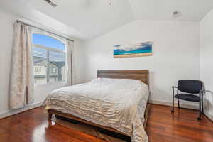 Bedroom with dark wood-type flooring and lofted ceiling