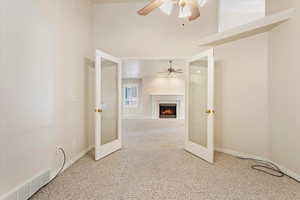 Interior space featuring french doors, a fireplace, a towering ceiling, and ceiling fan