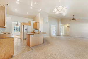 Kitchen featuring light brown cabinets, kitchen peninsula, decorative light fixtures, and white appliances