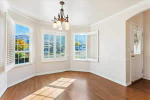 Unfurnished dining area featuring ornamental molding, an inviting chandelier, and hardwood / wood-style floors