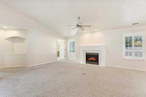 Unfurnished living room with ceiling fan, lofted ceiling, a fireplace, and carpet floors