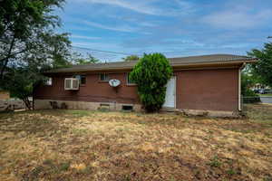 Back of property with a yard and an AC wall unit