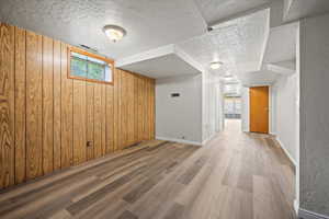 Interior space featuring wood walls, a textured ceiling, and hardwood / wood-style floors