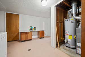 Basement with washer / clothes dryer, a textured ceiling, and water heater